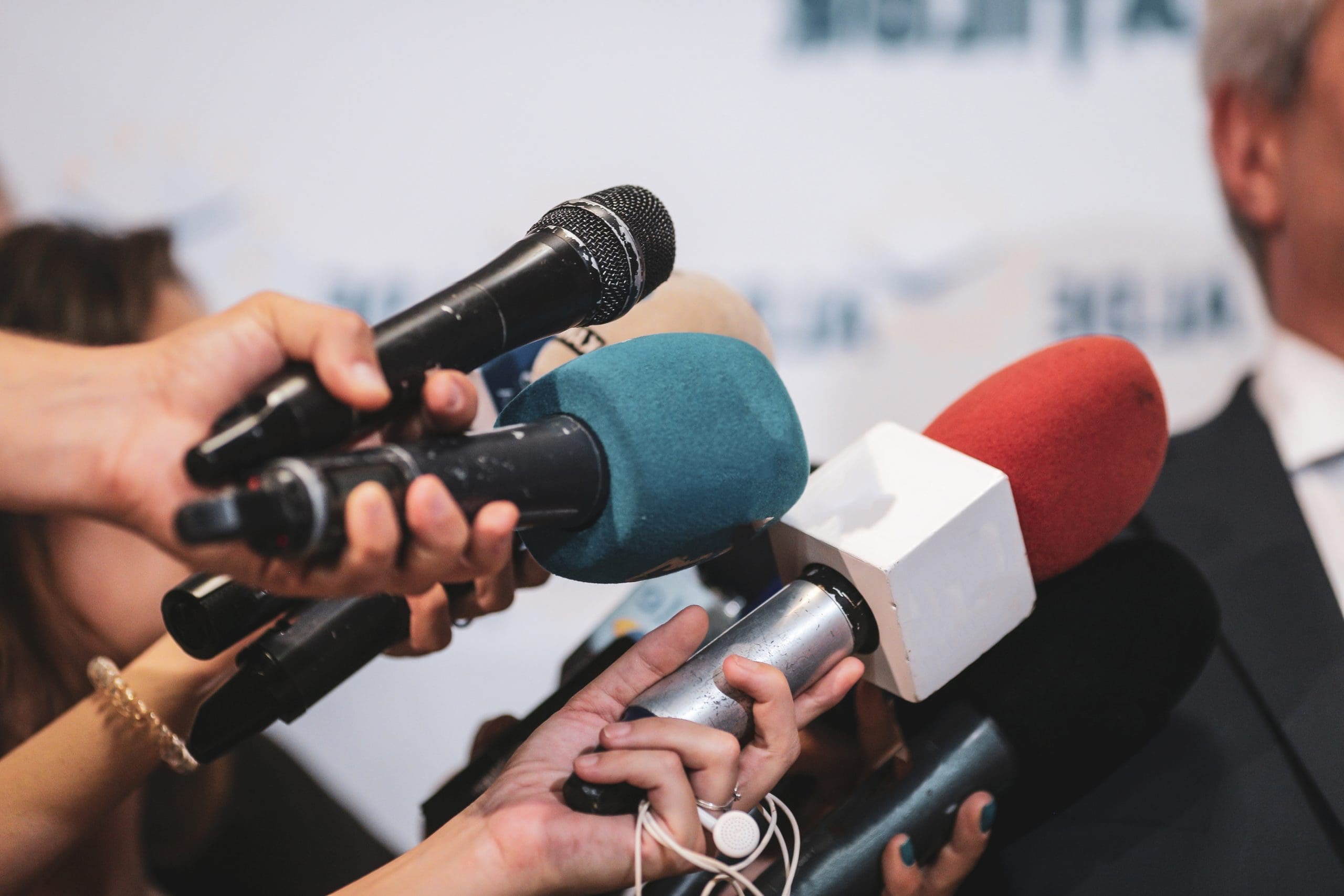 A man in a suit is being interviewed by reporters.