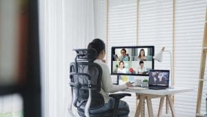 A woman is sitting at a desk and using a video conference.