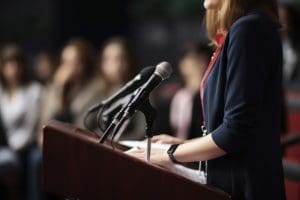 A woman is giving a speech at a podium.