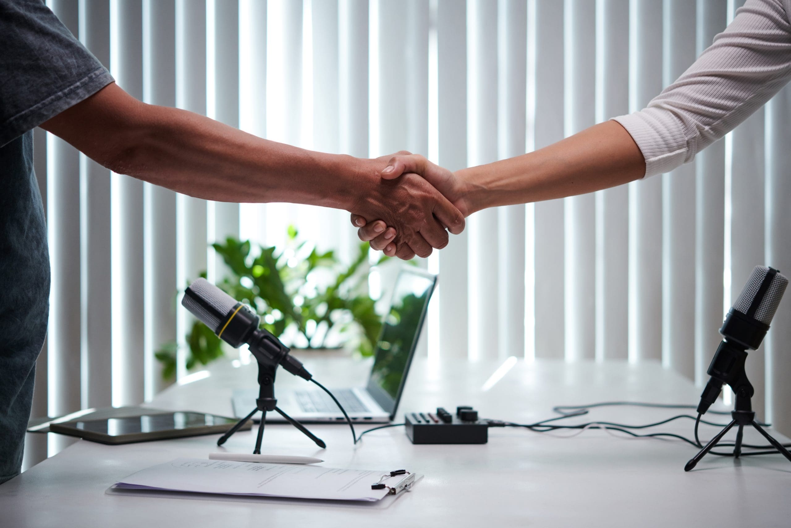 Two people shaking hands in front of microphones discussing podcasting and reputation management.
