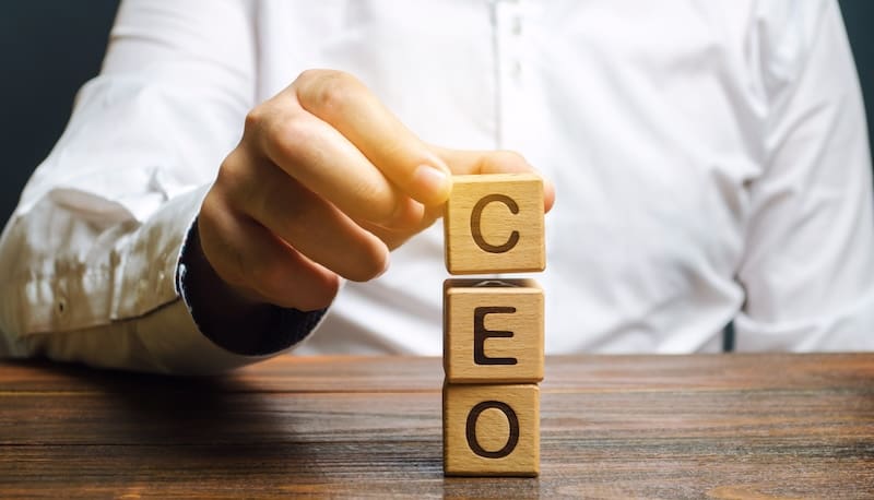 A man is holding a wooden block with the word CEO on it to represent CEO reputation management.