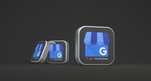 Three 3D icons of the Google My Business logo, featuring a blue storefront and the letter "G," are displayed on a dark background. The icons decrease in size from right to left.