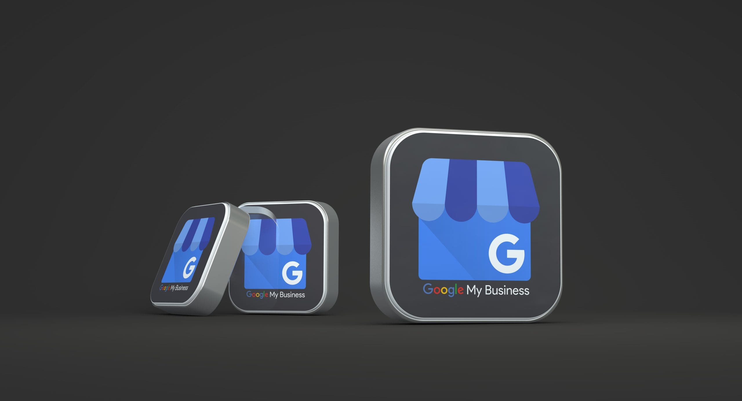 Three 3D icons of the Google My Business logo, featuring a blue storefront and the letter "G," are displayed on a dark background. The icons decrease in size from right to left.
