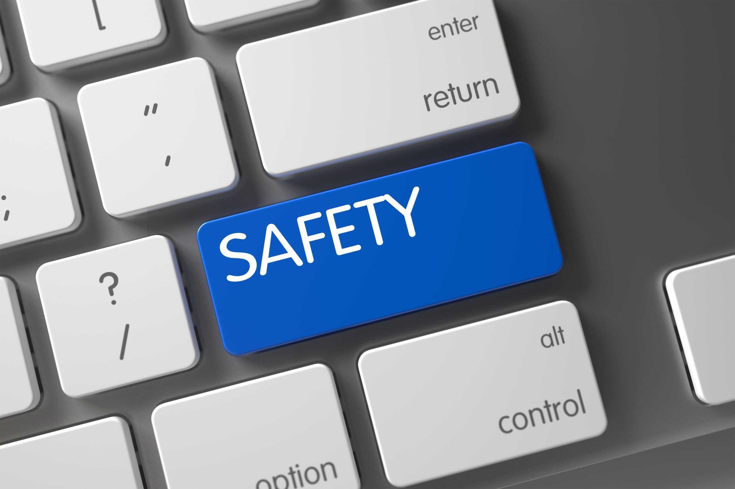 A close-up of a computer keyboard with a large blue key labeled "SAFETY" in place of the usual Enter key. Surrounding keys include return, shift, and alt.