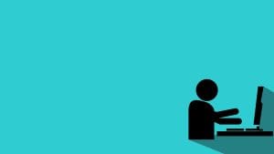 A minimalistic illustration of a person sitting at a desk, typing on a keyboard in front of a computer monitor, with a turquoise background and long shadow effect.