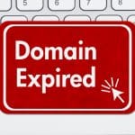 A red sign with white text reading "Domain Expired" and a mouse cursor icon is placed on a white computer keyboard.