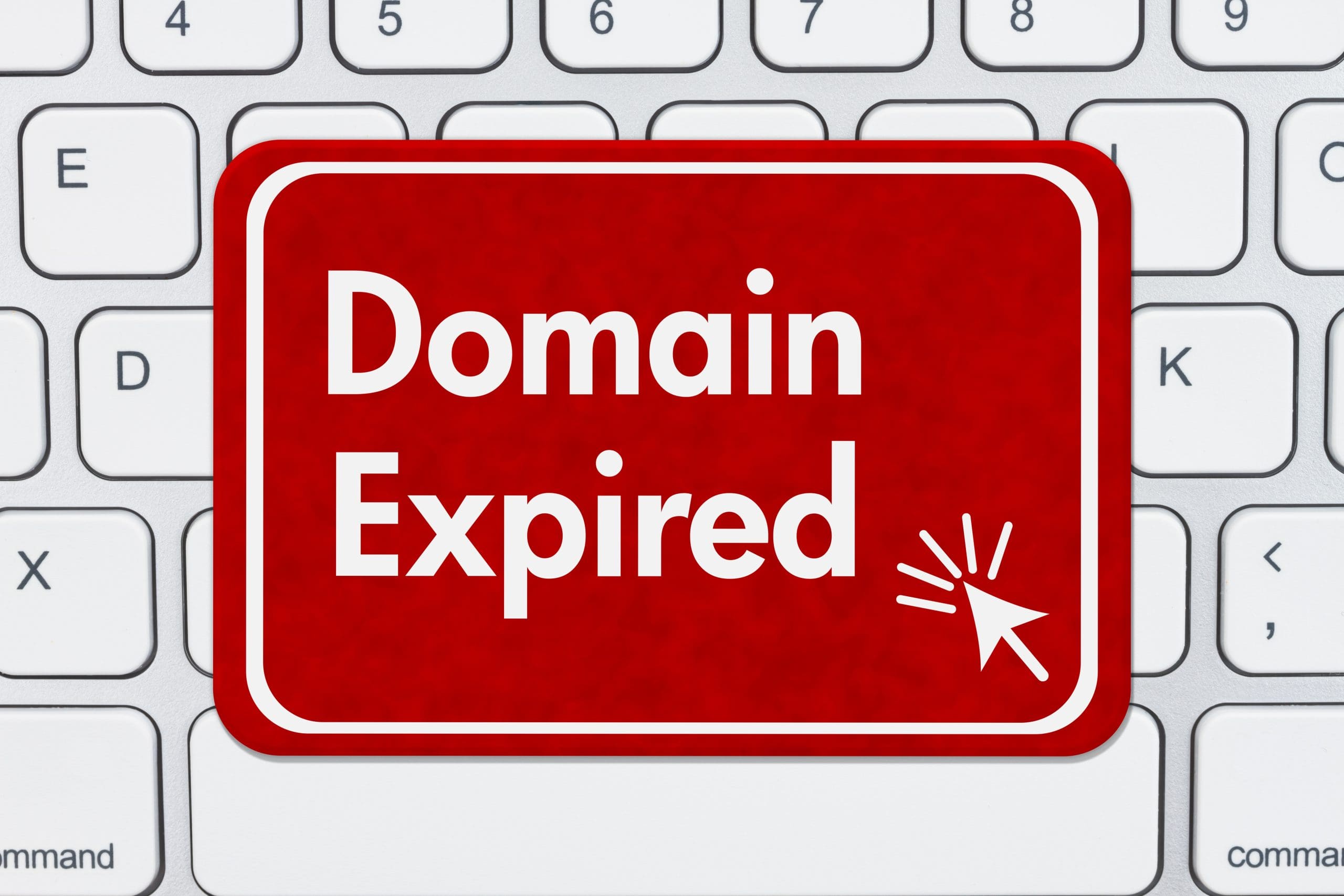 A red sign with white text reading "Domain Expired" and a mouse cursor icon is placed on a white computer keyboard.