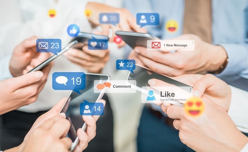 Several people hold smartphones, surrounded by digital icons for likes, comments, messages, and social media notifications, symbolizing the active engagement of an internet influencer on popular social media platforms.